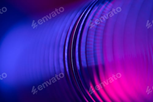 Vista previa: Primer plano de anillos de resorte de metal en espiral en un estado comprimido en luz de neón roja