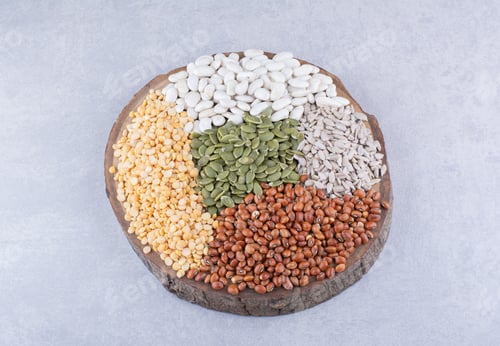 Preview: Assortment of grain, seeds and legume on a slice of log on marble background