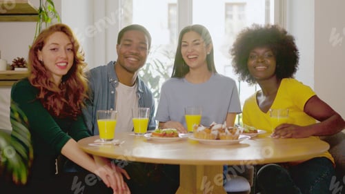 Preview: Multiethnic friends smiling at camera while eating breakfast at home