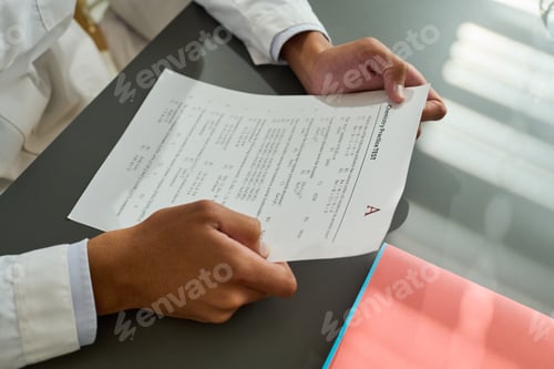 Preview: Hands of African American teenage guy holding paper with exam test