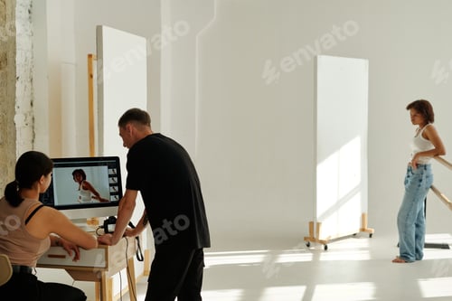 Preview: Two young colleagues in casualwear discussing new shots on computer screen