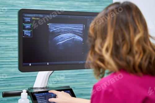Preview: Female physician consulting something on ultrasound equipment while working in a medical center.
