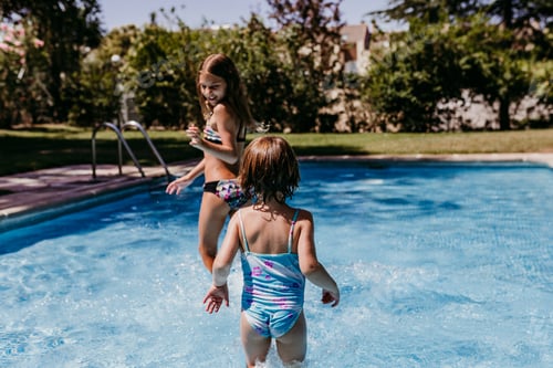 Preview: two beautiful sister kids at the pool playing, running and having fun outdoors. Summertime
