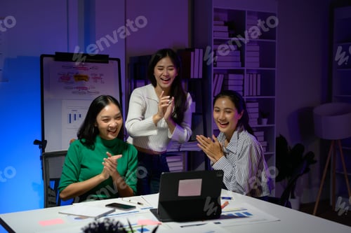 Preview: Group of Young Professionals Celebrating Success During a Late-Night Office Meeting with Laptops and