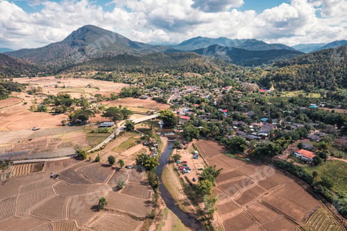 Preview: Tranquil local village with river flowing through among the valley and rice plantation on dry season