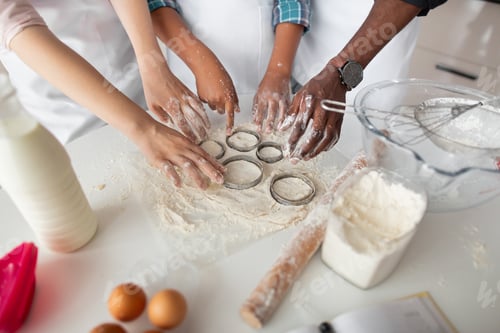 Preview: Cutting out round shapes from rolled out dough to prepare home made cookies. Hands of multiethnic
