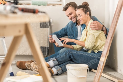 Preview: happy young couple using digital tablet during renovation in new house