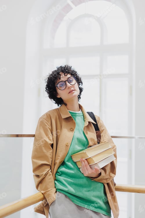 Preview: thoughtful woman with stack of books in hands in library or coworking. successful female student