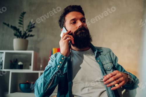 Preview: A casual entrepreneur is having a phone call with an important client while sitting at his home