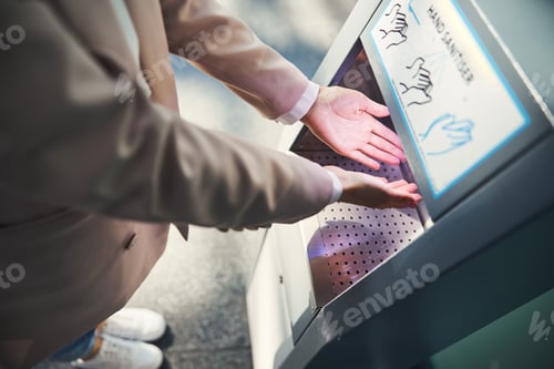 Preview: Female person using automatic hand sanitizer at airport