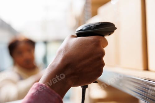 Preview: African american warehouse worker hand holding barcode scanner
