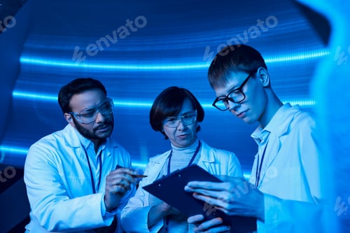 Preview: advanced learning, indian scientist pointing at clipboard near young intern in discovery center
