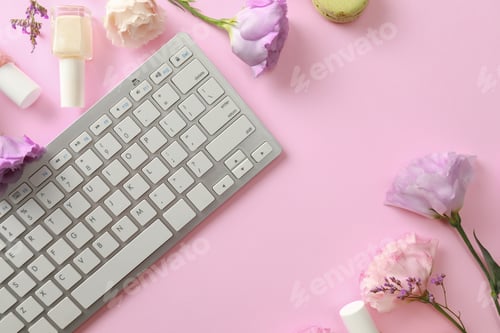 Preview: Flat lay composition with keyboard and flowers on pink background. Beauty blogger's workplace