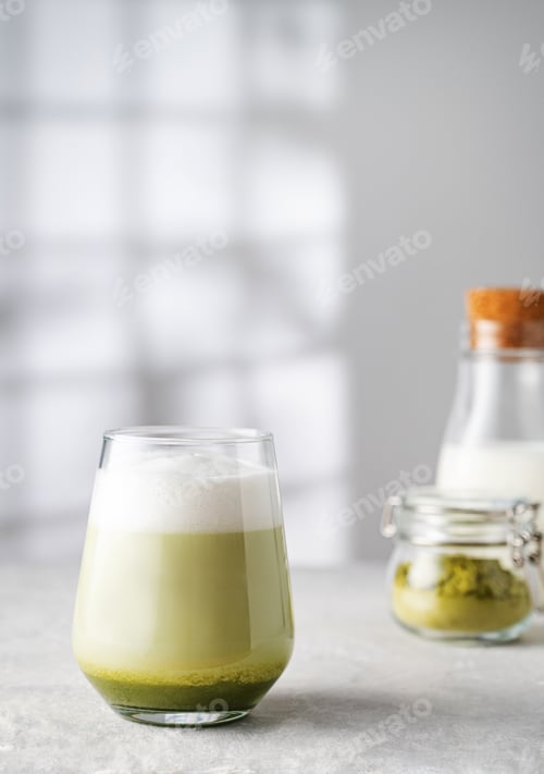 Preview: Green matcha latte in a glass on a gray background with morning shadows from the window
