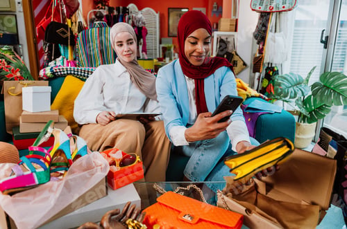 Preview: Muslim women friends enjoying online shopping unboxing fashion purchases at home