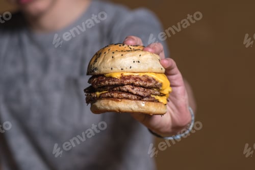 Preview: Closeup of a cheeseburger held by a man