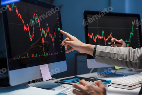 Preview: Business people analyzing financial charts on computer screens in office at night