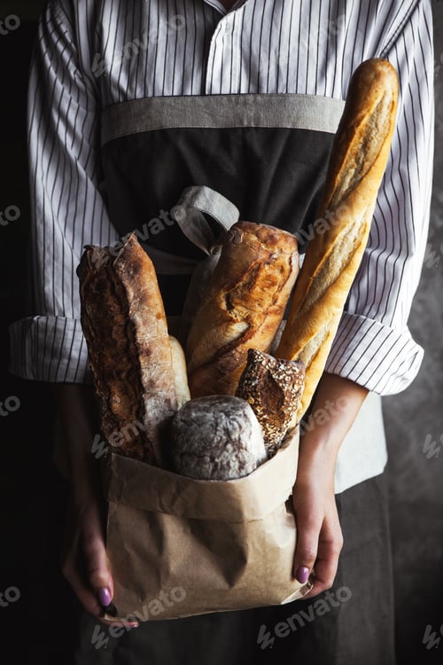 Preview: French baguettes in female hands on a black background. homemade baking
