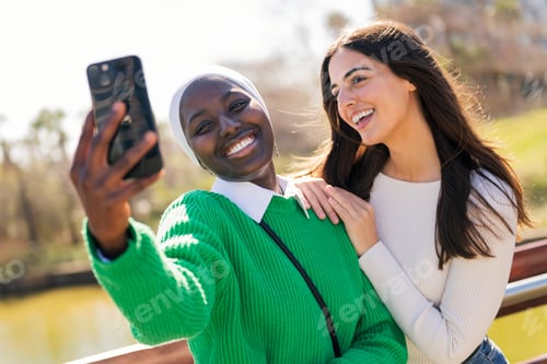 Preview: female friends having fun taking selfie with phone