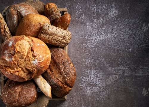 Preview: Background with Different Types of Bread put in a wooden box on dark surface.