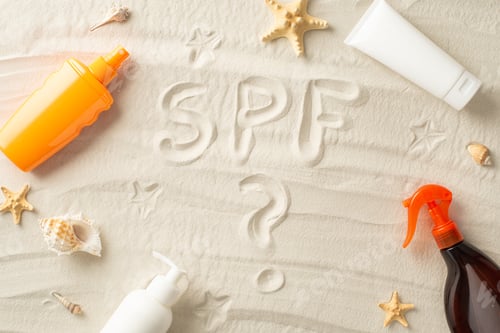 Preview: Sun protection products concept. High angle view of SPF inscription, tube,spray and bottle
