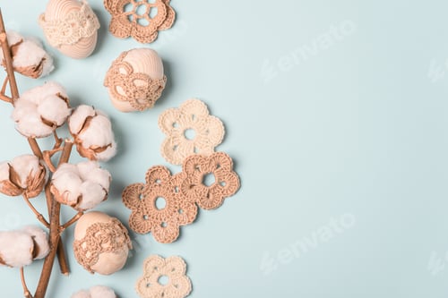 Preview: Craft eggs, knitted and cotton flowers on blue background. Top view. Copy space