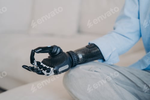 Preview: Cyber hand of disabled person which is sitting in lotus pose on couch. Robotic arm in meditation.