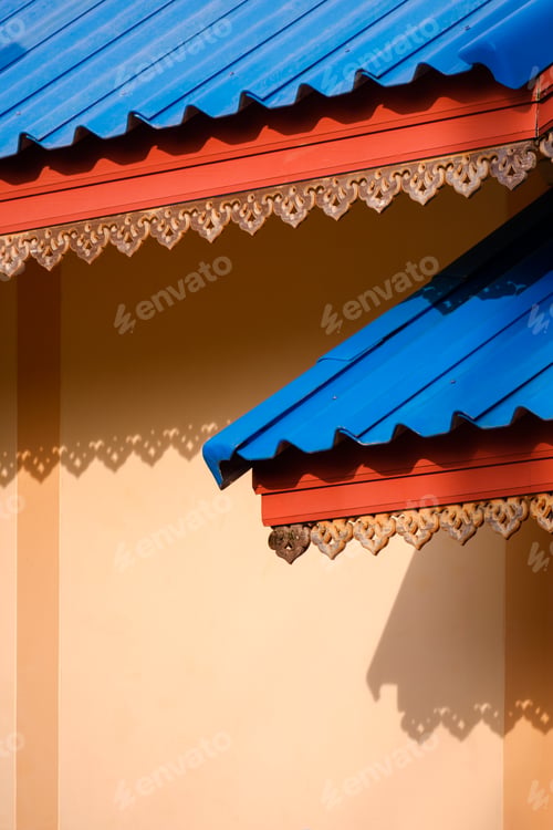 Preview: Thai traditional perforated wooden roof eaves with blue fiber cement tile roofs of vintage house
