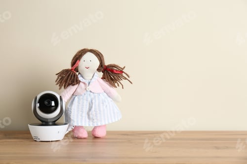Preview: Baby monitor and toy on wooden table, space for text. CCTV equipment