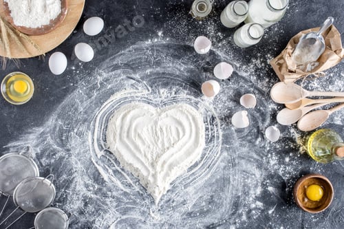 Preview: top view of heart sign made of flour and various ingredients for baking on dark surface