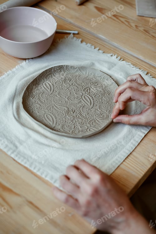 Preview: Beautiful raw clay plate with ornament on table in workshop