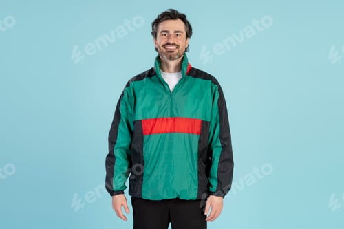 Preview: Smiling coach wearing green and black vintage jacket on blue background