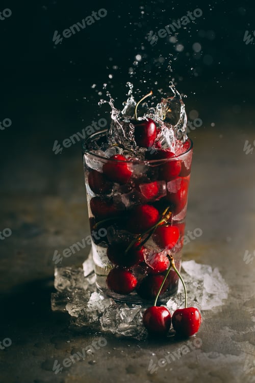 Preview: Splashing cherries in a glass with ice on dark background