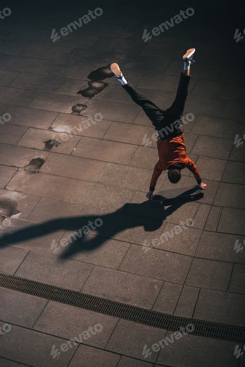 Preview: high angle view of skateboarder riding upside down on hands
