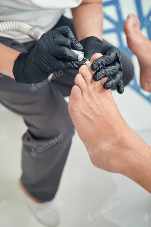 Preview: Man having hardware pedicure procedure in cosmetology clinic