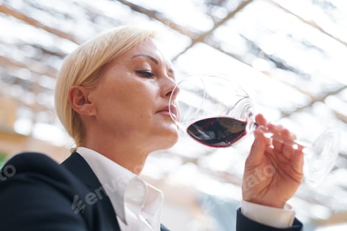 Preview: Serious winery expert holding bokal of red wine evaluating its smell