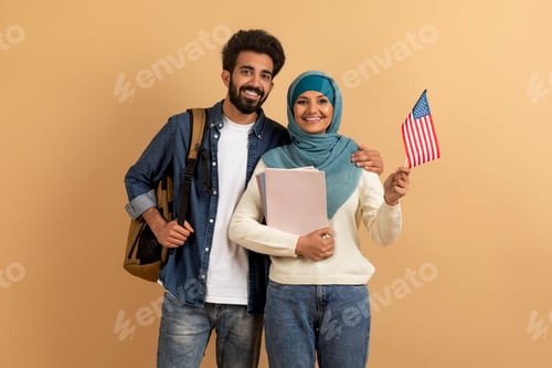 Preview: Cheerful muslim students young man and woman in hijab holding american flag