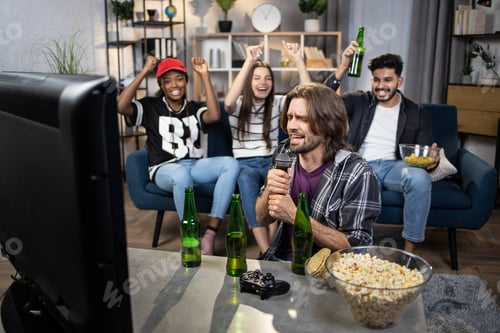 Preview: Group of four multicultural people singing karaoke at home