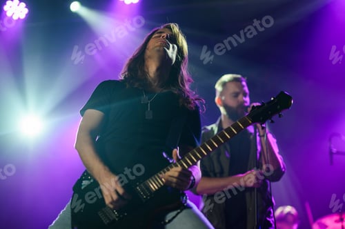 Preview: Guitarist performing with passion on stage under purple lights