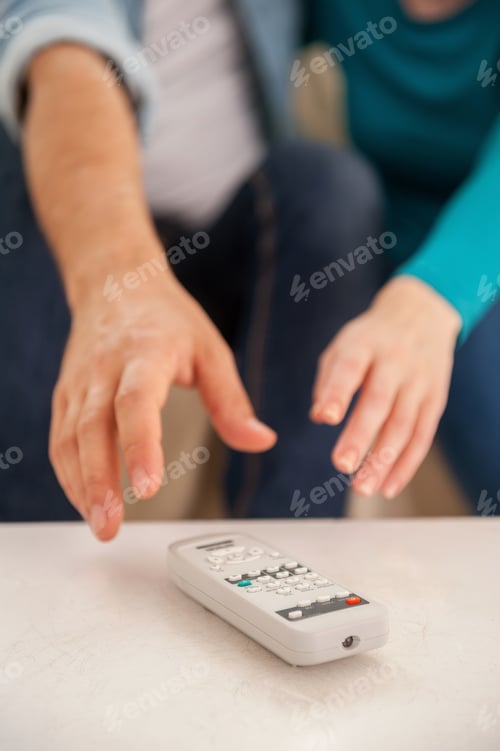 Preview: Struggling for remote control. Close-up of two hands stretching to the remote control