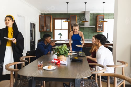 Preview: Teens enjoying lively celebration at home, sharing food and laughter around table