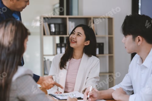 Preview: Smiling businesswoman engaging in a conversation with her colleagues at the meeting table.