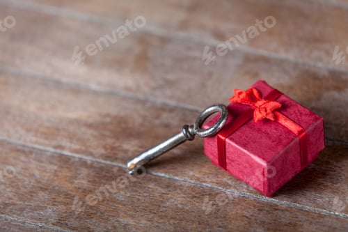 Preview: Retro key and little red gift on wooden table.