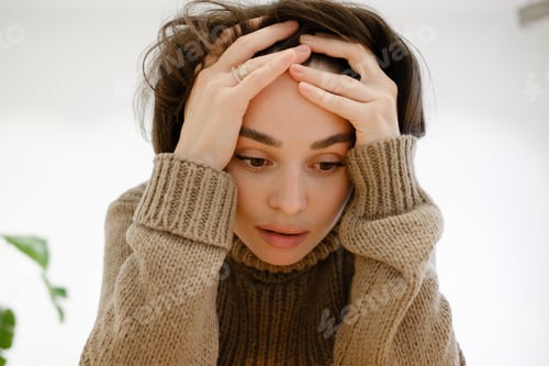 Preview: Portrait of a thoughtful woman with hands on her head wearing a sweater