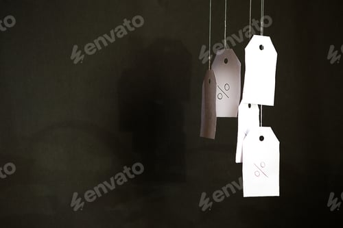 Preview: White tags with the percent sign hang on strings on a black background