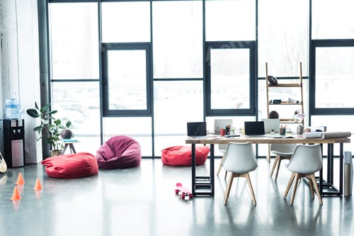 Preview: modern design of spacious loft office with bean bag chairs and table with laptops