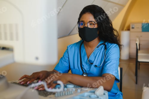 Preview: Young cheerful African woman operator in mask of an ultrasound scanning machine