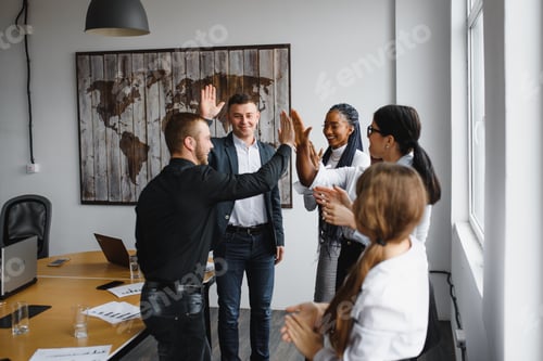 Preview: Successful creative multiracial business team giving high five.