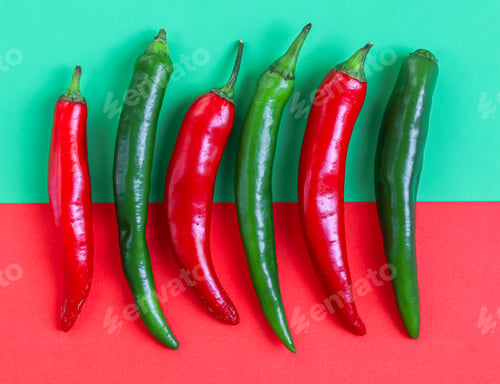 Preview: Six hot green and red chili peppers lie horizontally in a row on a red-green background