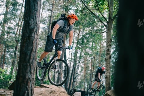 Preview: active young trial bikers riding at beautiful forest